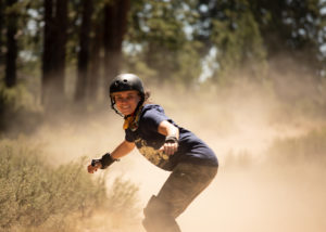 Racheal Cecil kicks up dust while racing onewheels in the desert.