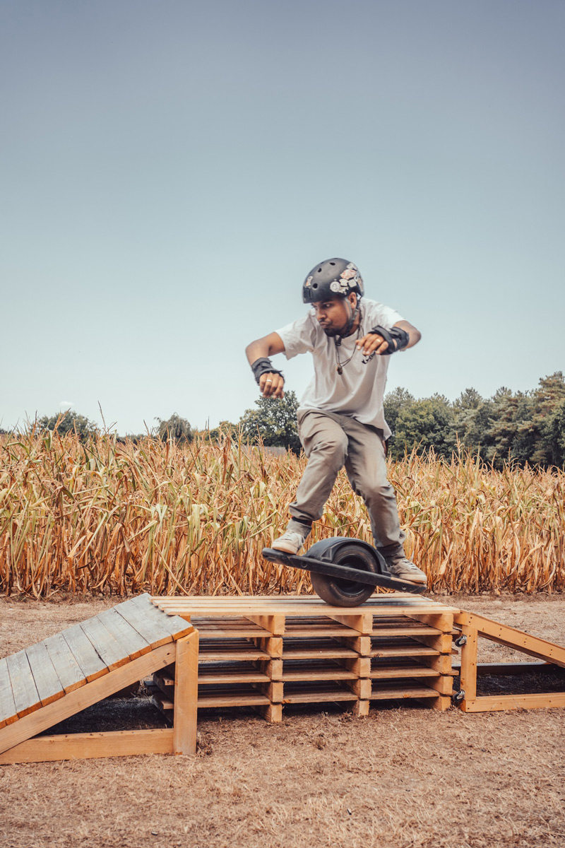 Muddi rides a Onewheel Pint over a wooden ramp feature in the Float Line Fest race.